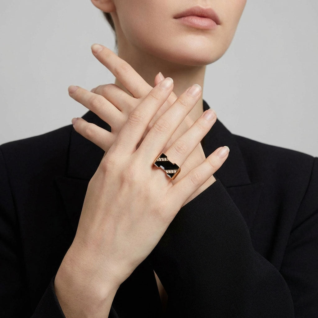 Modell mustas jakis esitleb massiivset kullatud sõrmust musta emailiga