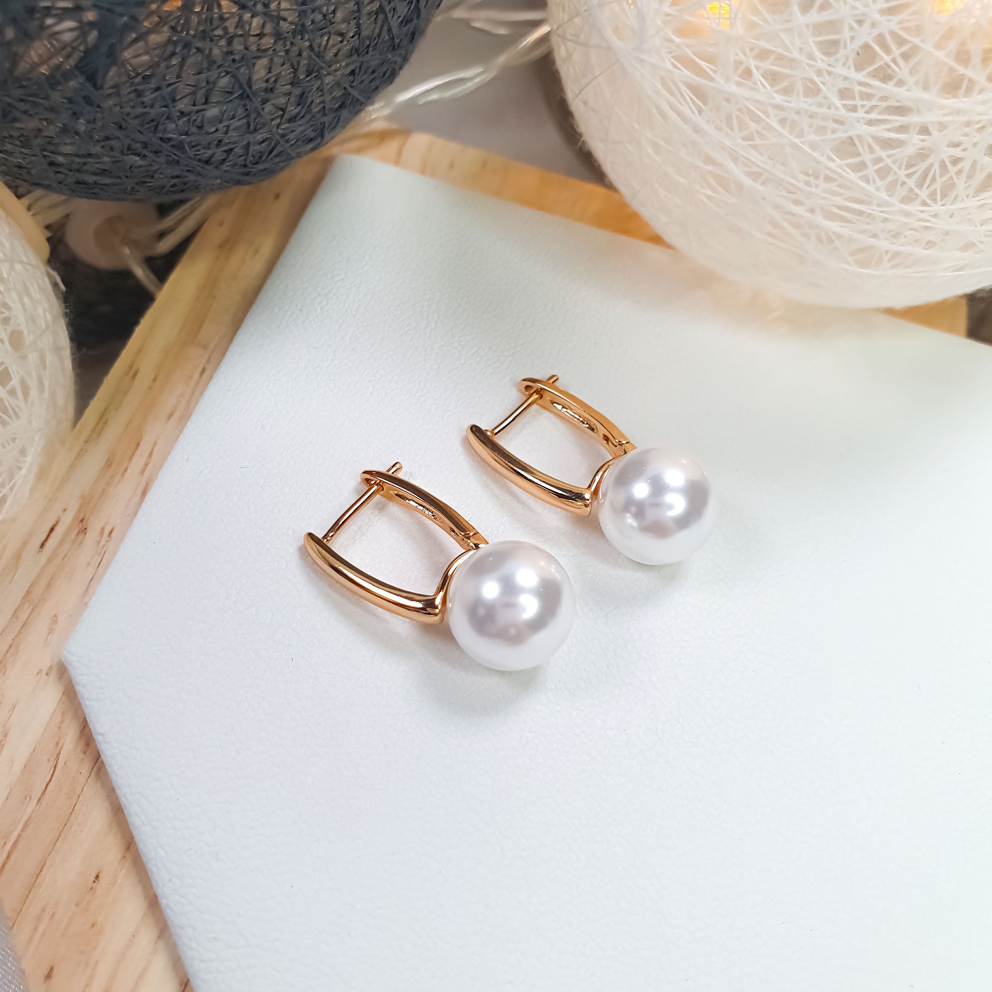 Noapaļoti auskari ar balti spīdīgu pērli tuvplānā