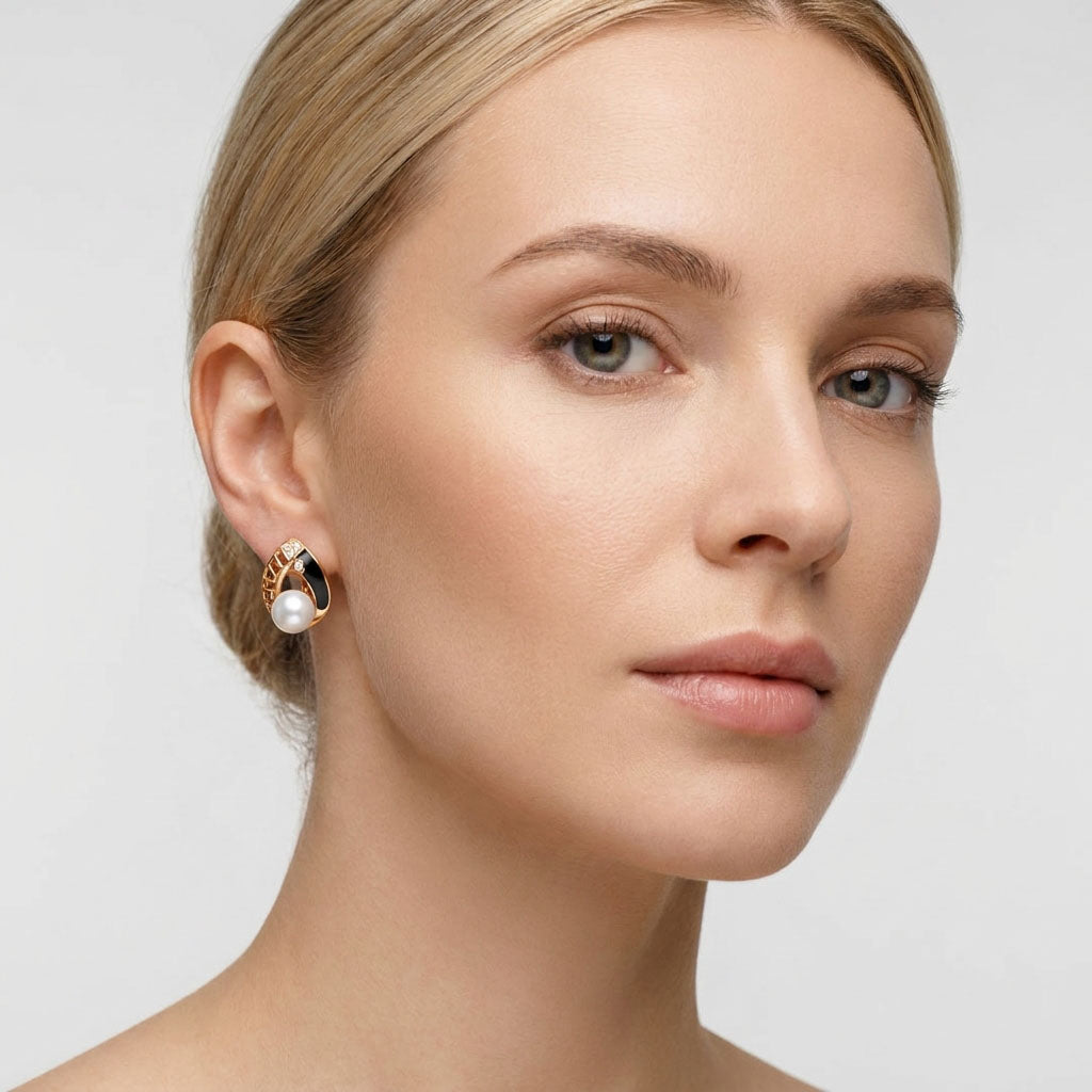 Модель с позолоченной серьгой с жемчужиной в ухе, видны чёрная эмаль и ажурный узор