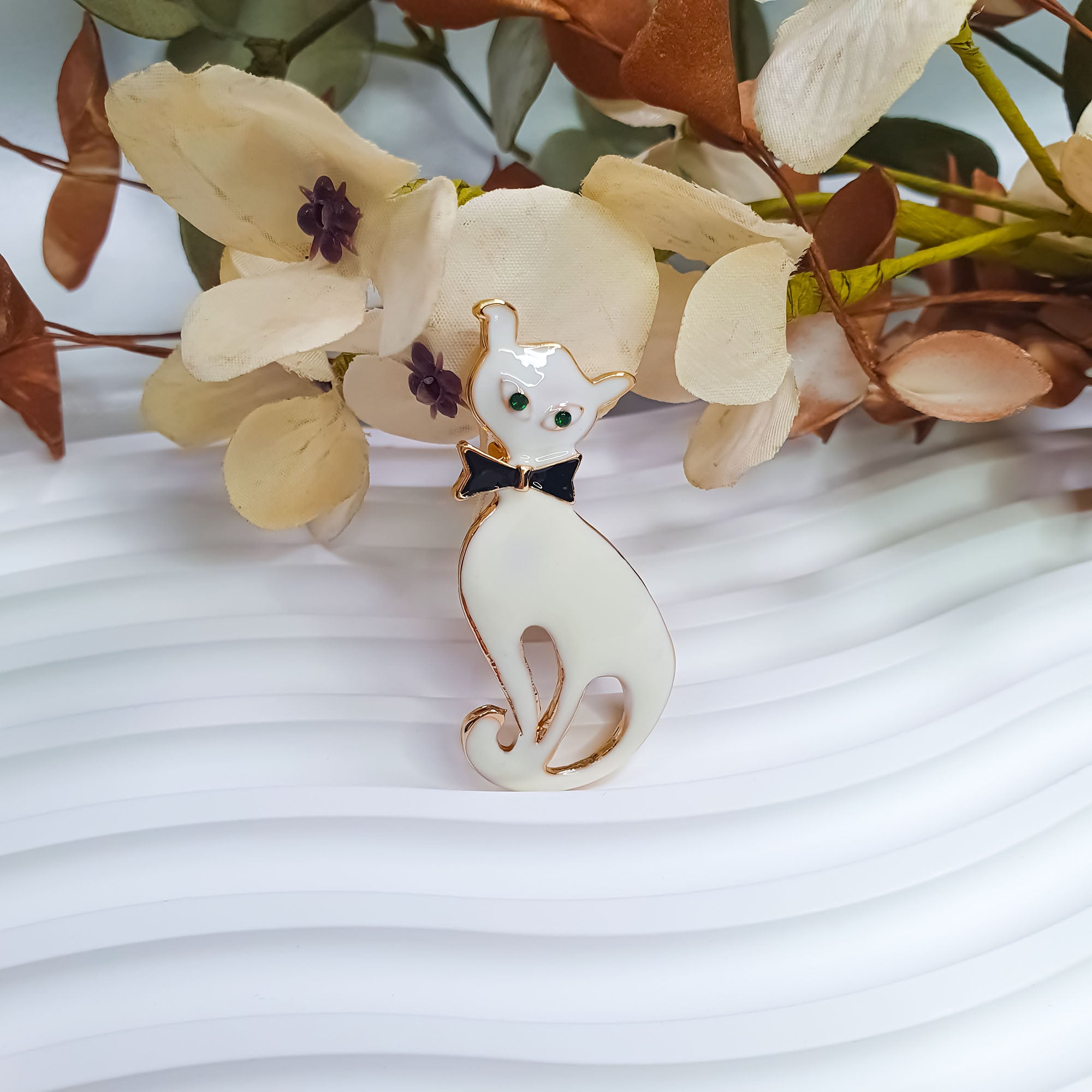 Dzīvnieka formas piespraude ar baltu emalju tuvplānā