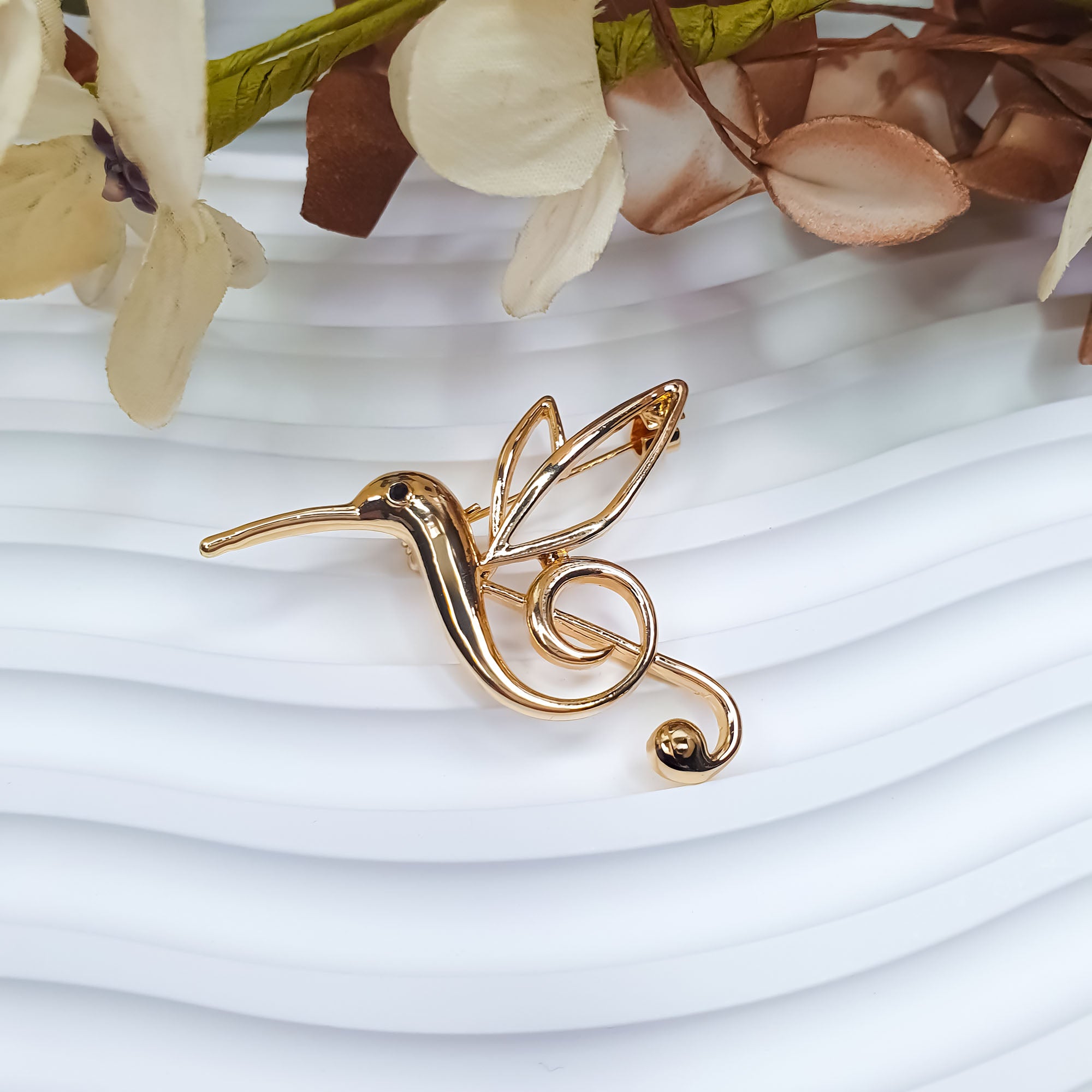 Stilizēta kolibri formas piespraude ar plūstošu kontūru